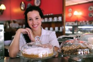 Smiling woman at café with delicious desserts.